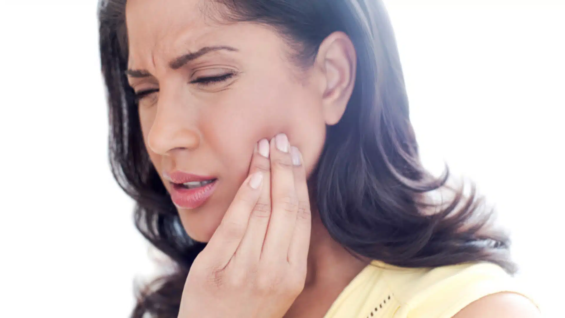 Close-up of woman touching cheek with open mouth, suffering from jaw pain