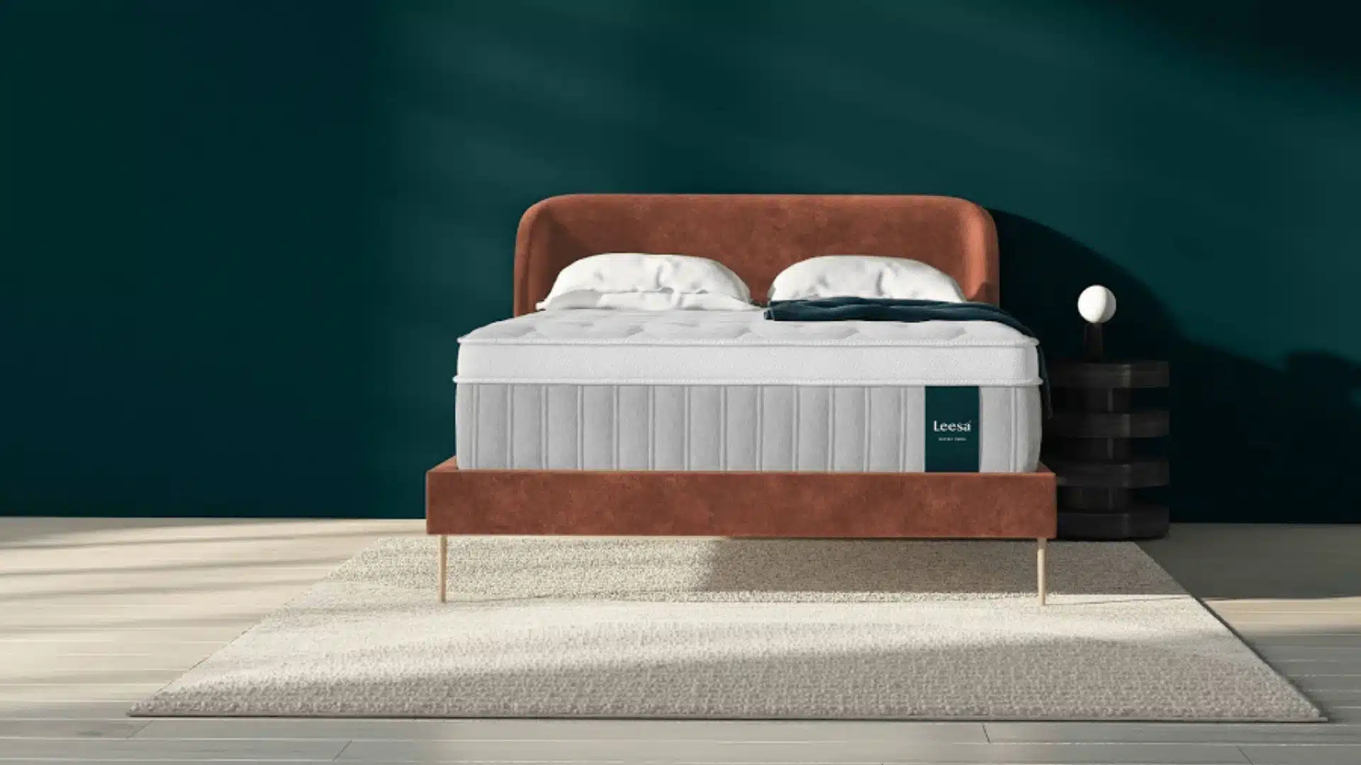 Leesa Sapira Chill mattress displayed on a rust-colored upholstered bed in a modern bedroom.