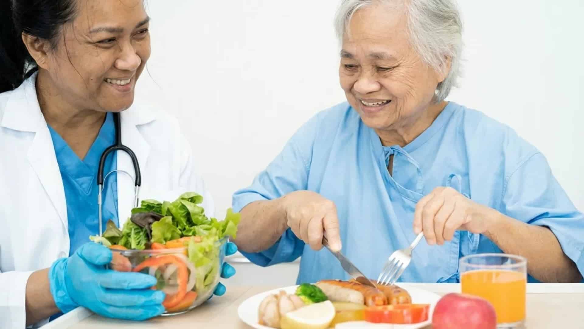 elderly-woman-eating-food-with-nurses-help