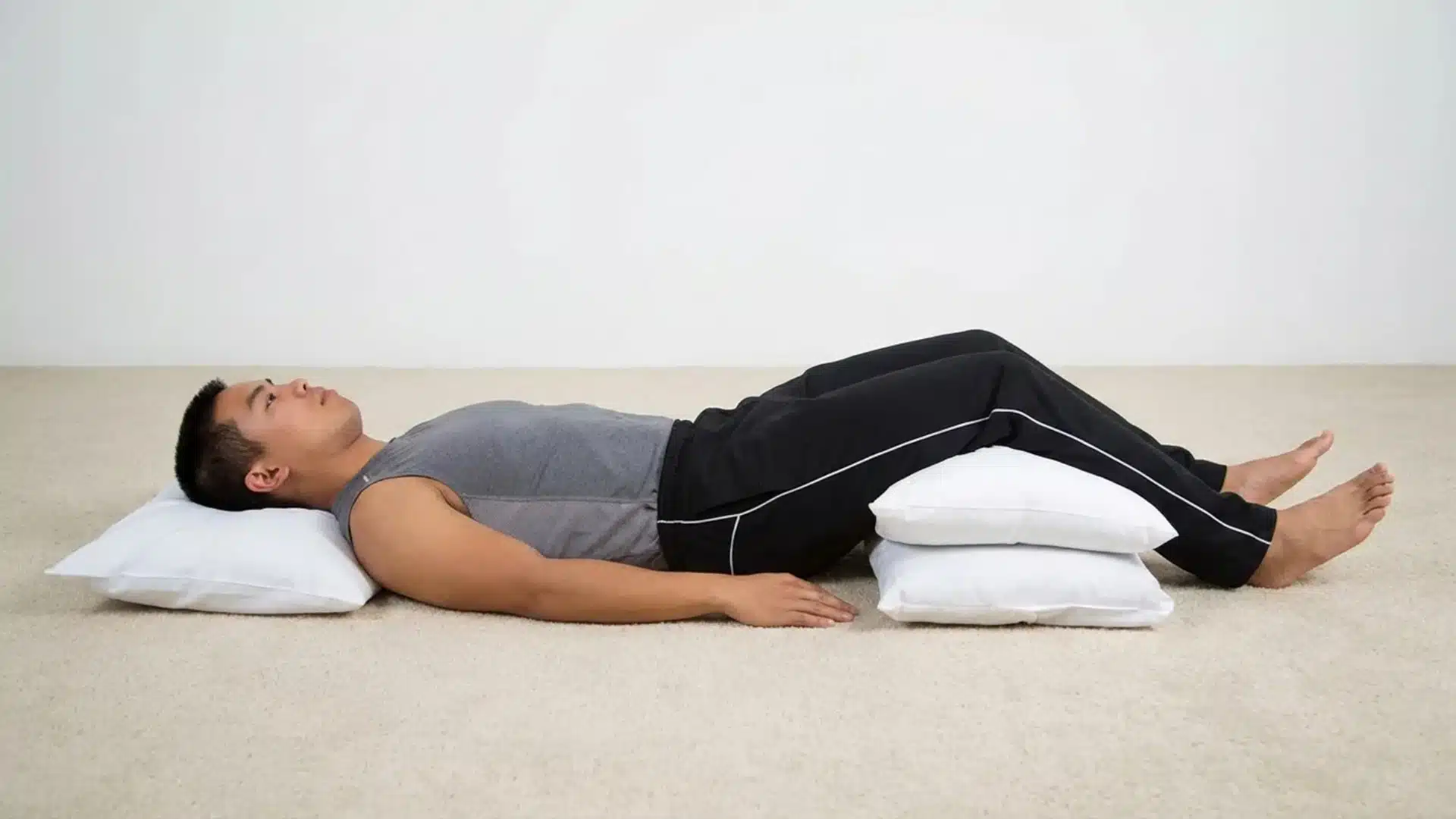 Man lying on his back with pillows under knees to support a sleep position pose (1)