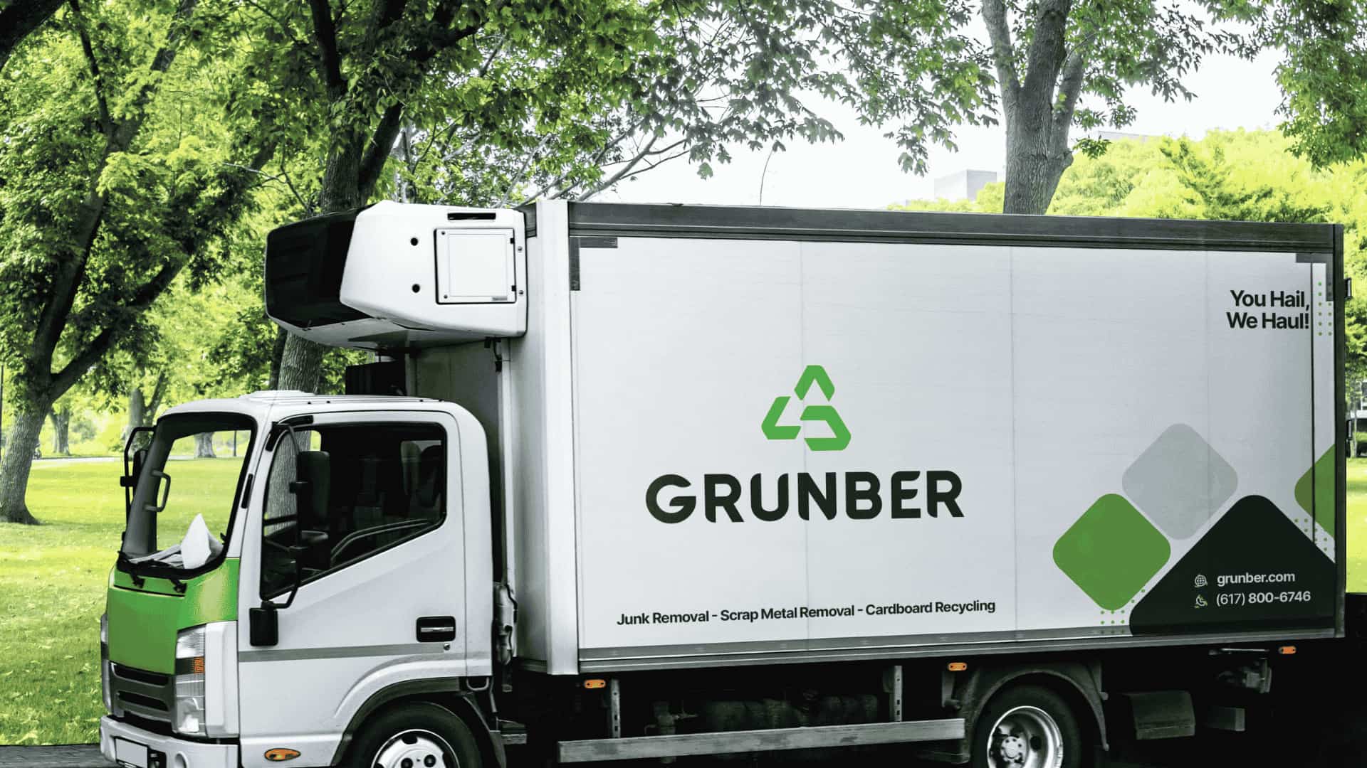 Grunber junk removal truck parked under trees with green recycling branding on the side.