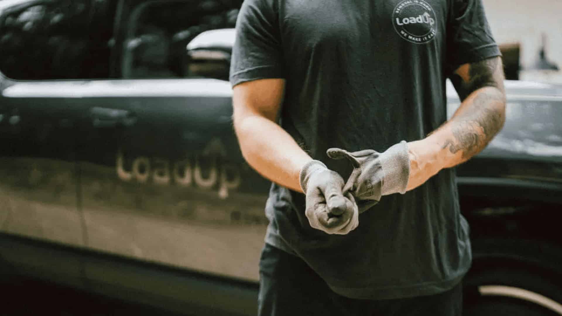 LoadUp worker wearing gloves standing in front of a branded pickup truck.