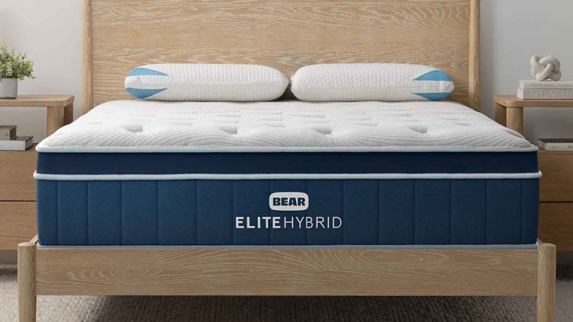 Bear Elite Hybrid cooling mattress with tufted pillow top on wooden bed frame in cozy neutral bedroom.
