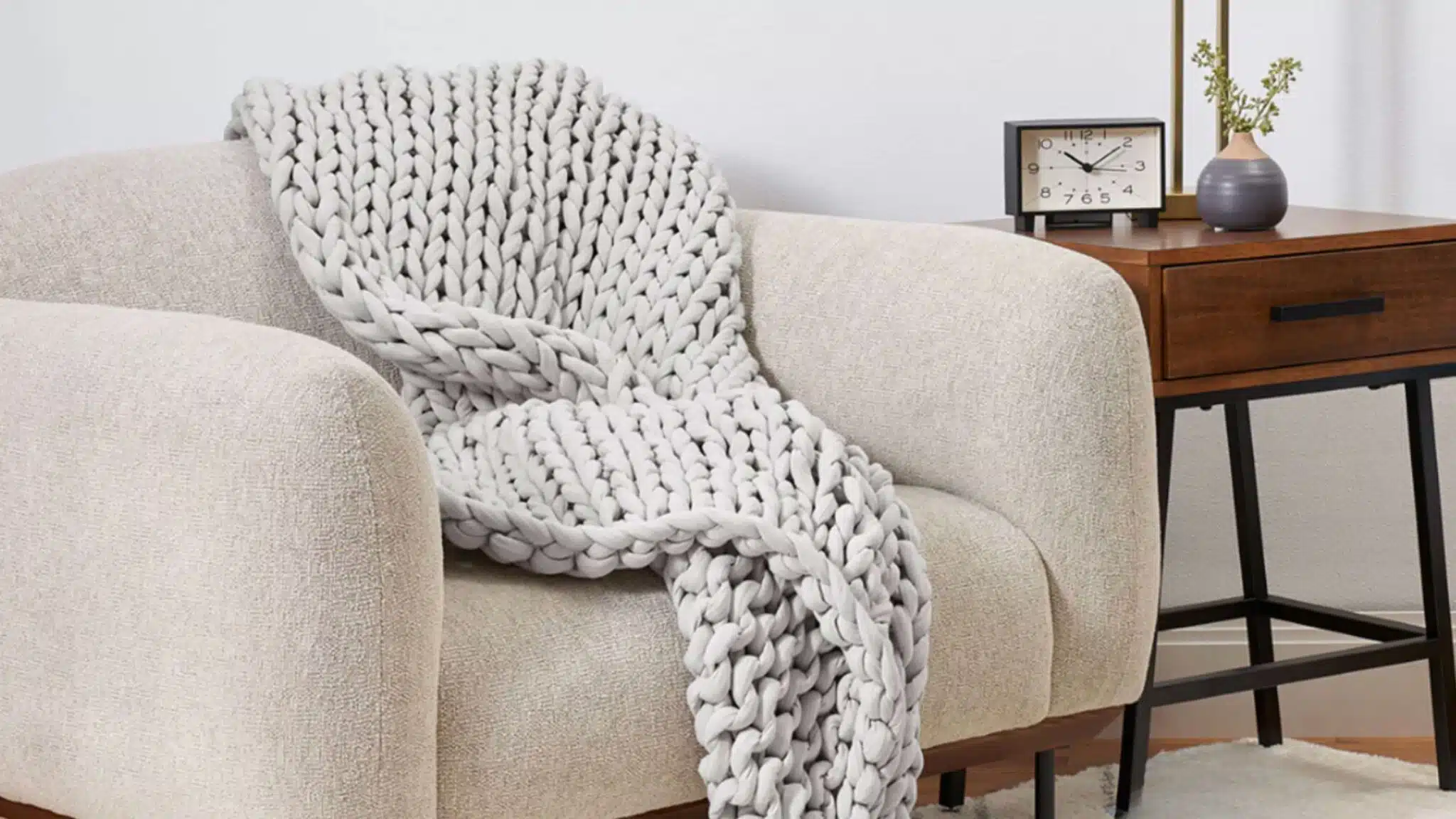 Chunky white knit blanket draped over an armchair in a living room