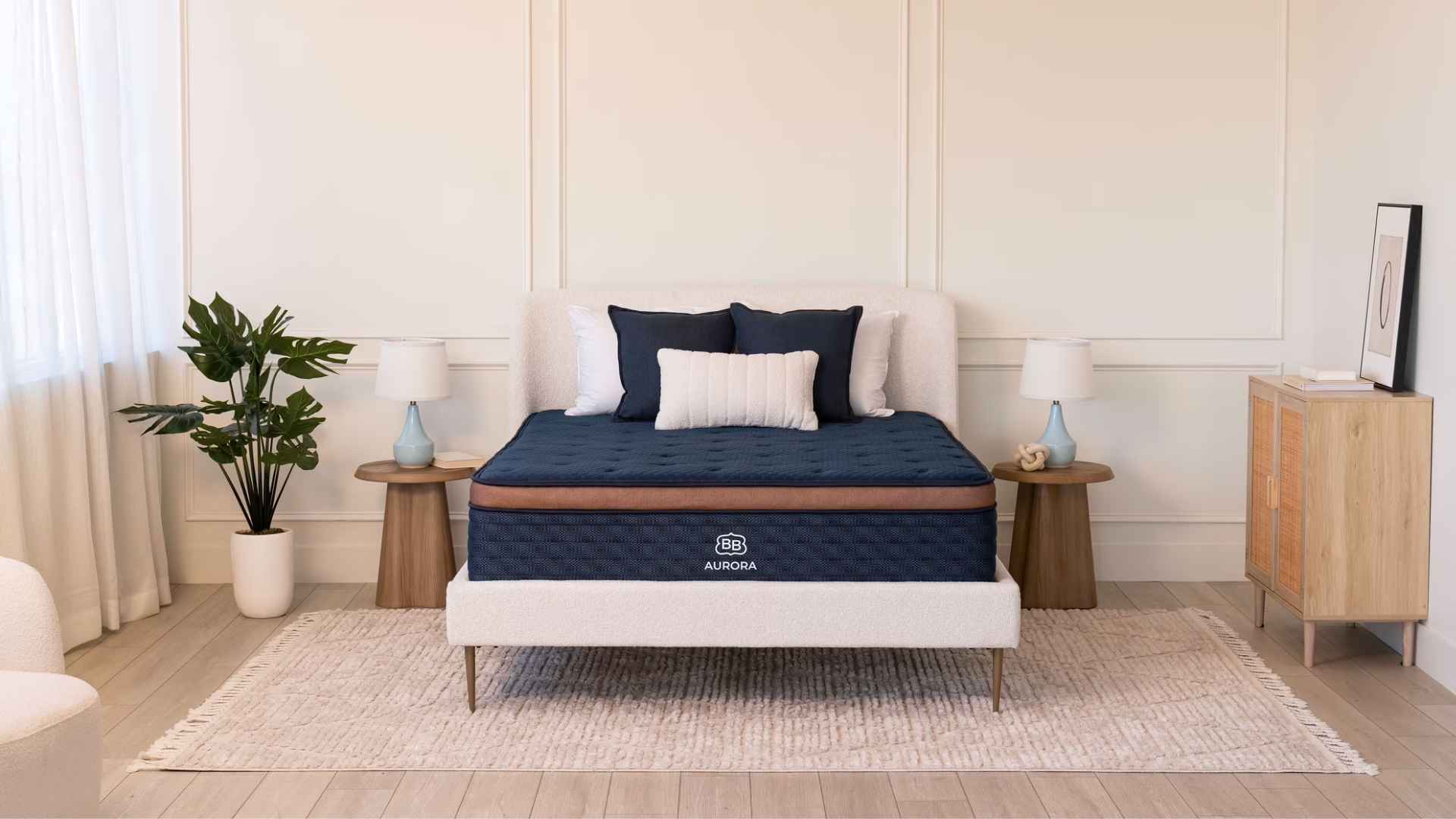 Brooklyn Bedding Aurora hybrid cooling mattress in minimalist bedroom with navy bedding and soft lighting.