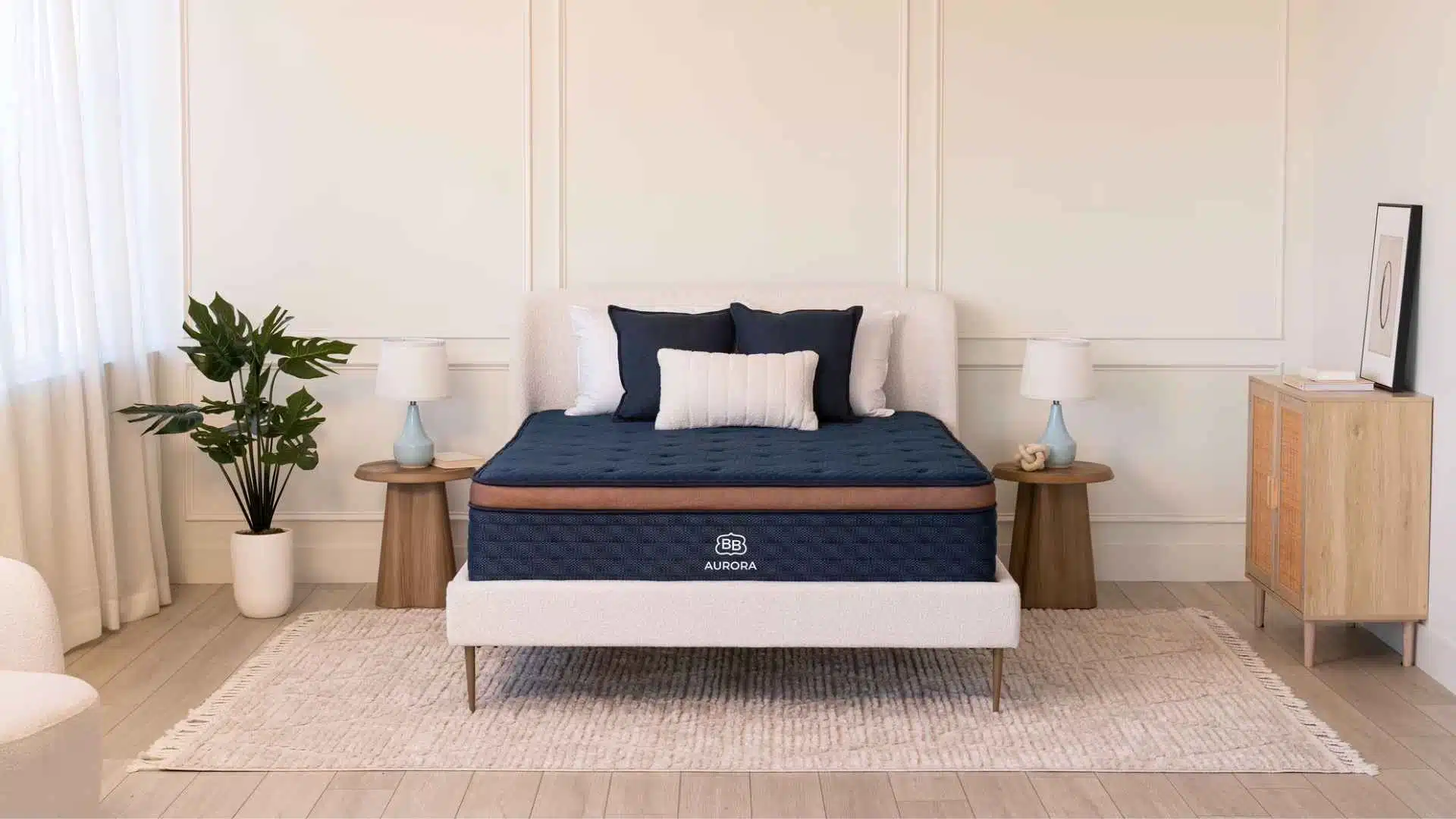 Brooklyn Bedding Aurora hybrid cooling mattress in minimalist bedroom with navy bedding and soft lighting.