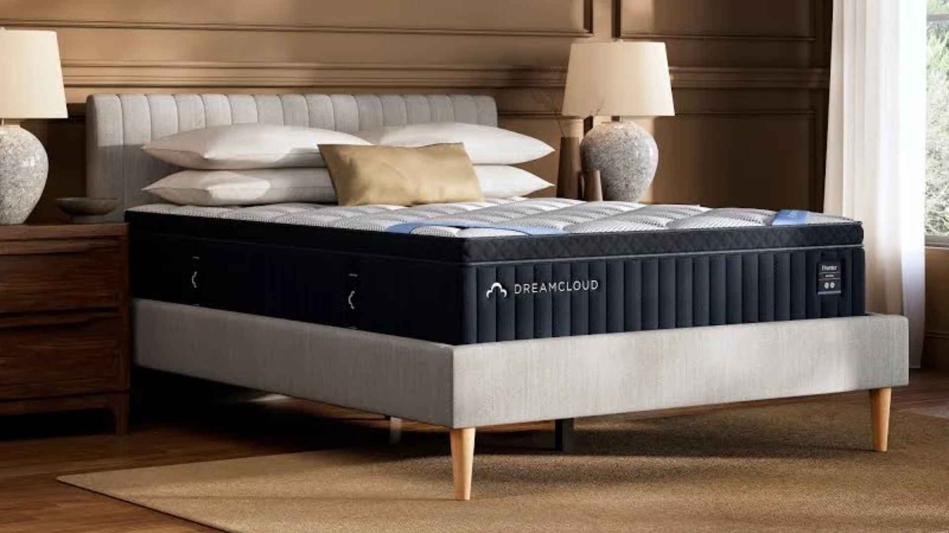 DreamCloud Premier hybrid mattress with quilted top in warm bedroom featuring lamps and upholstered bed.