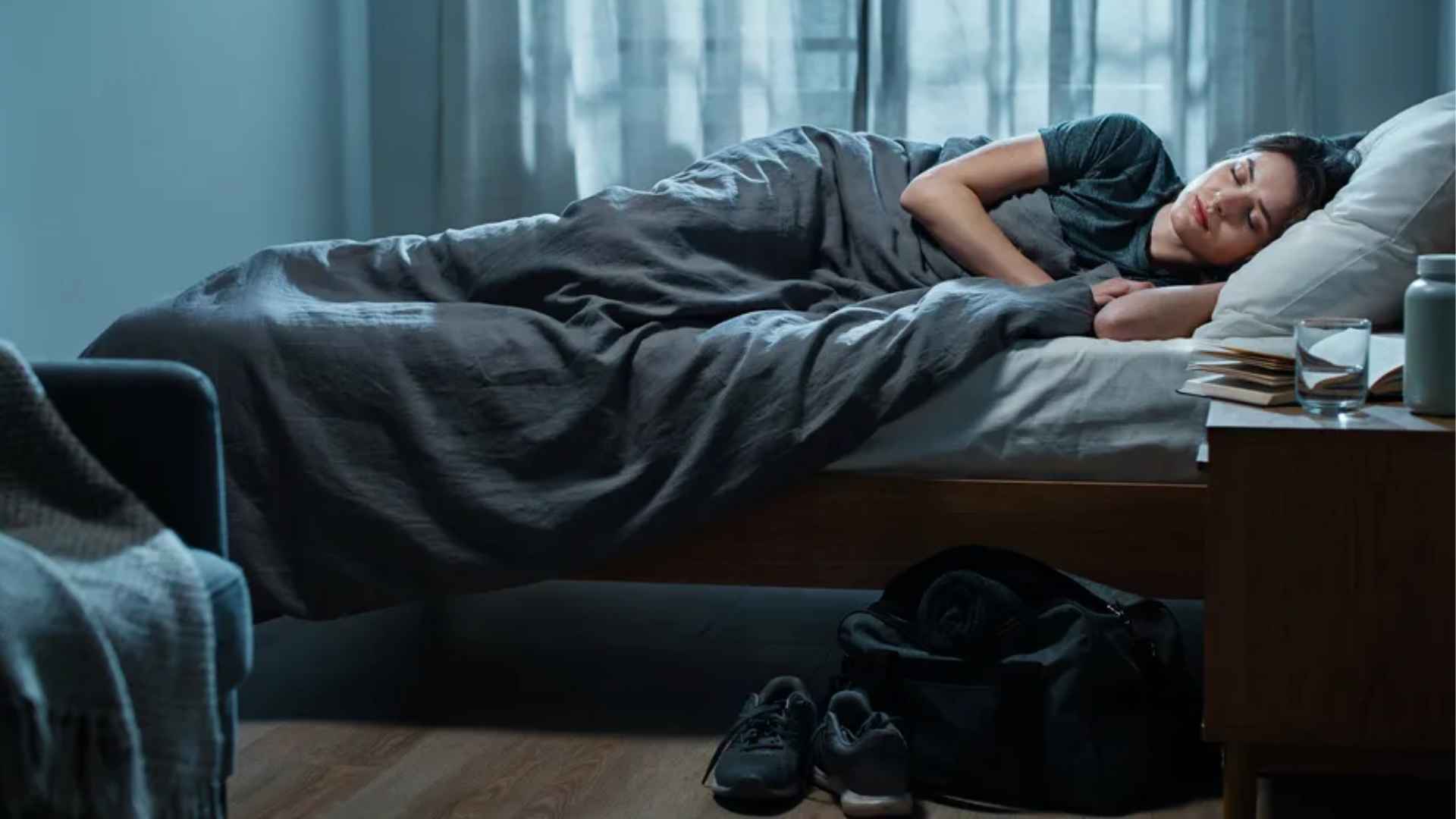 Person resting peacefully in a softly lit bedroom at night, suggesting post-workout recovery and calm sleep environment.