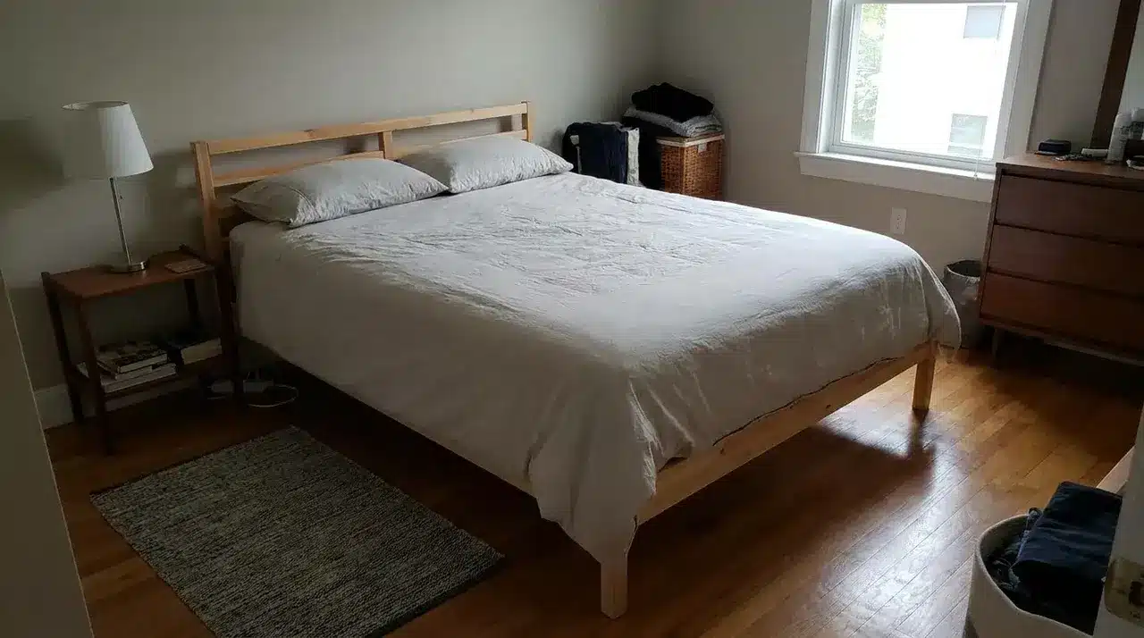 Full-size mattress with white bedding in a cozy modern bedroom with natural wood furniture