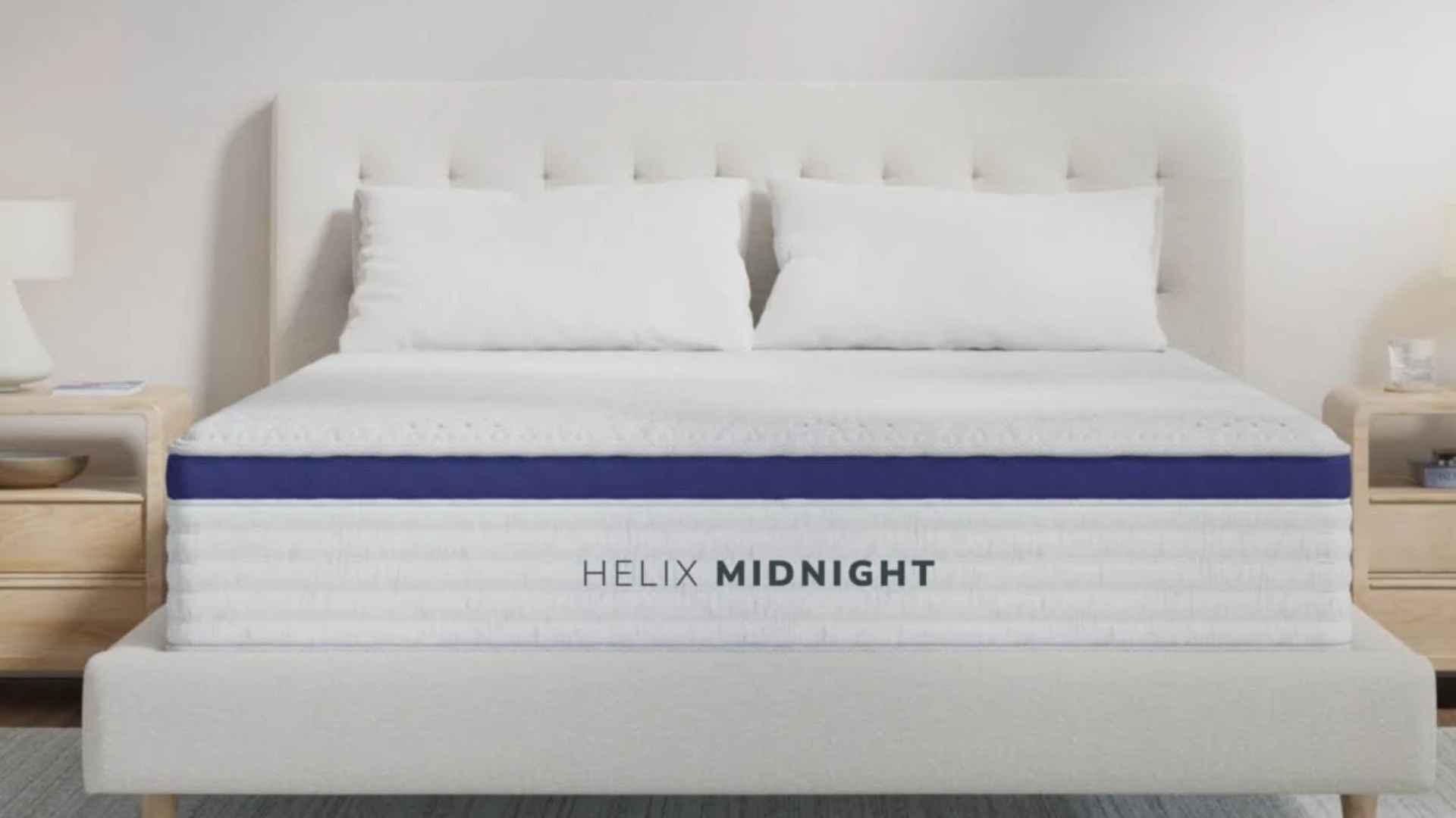 Minimal bedroom with white upholstered bed, Helix Midnight mattress, two pillows, and bedside tables with lamps