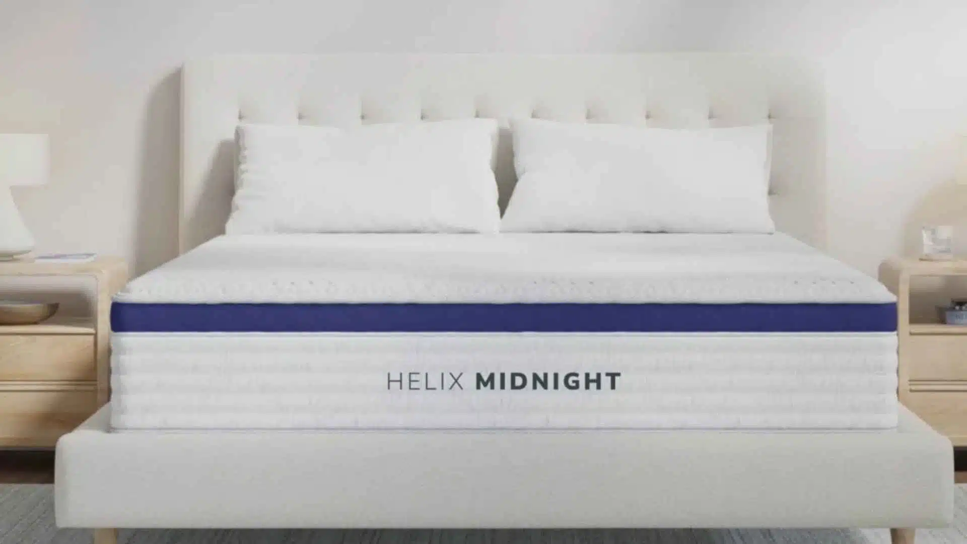 Minimal bedroom with white upholstered bed, Helix Midnight mattress, two pillows, and bedside tables with lamps