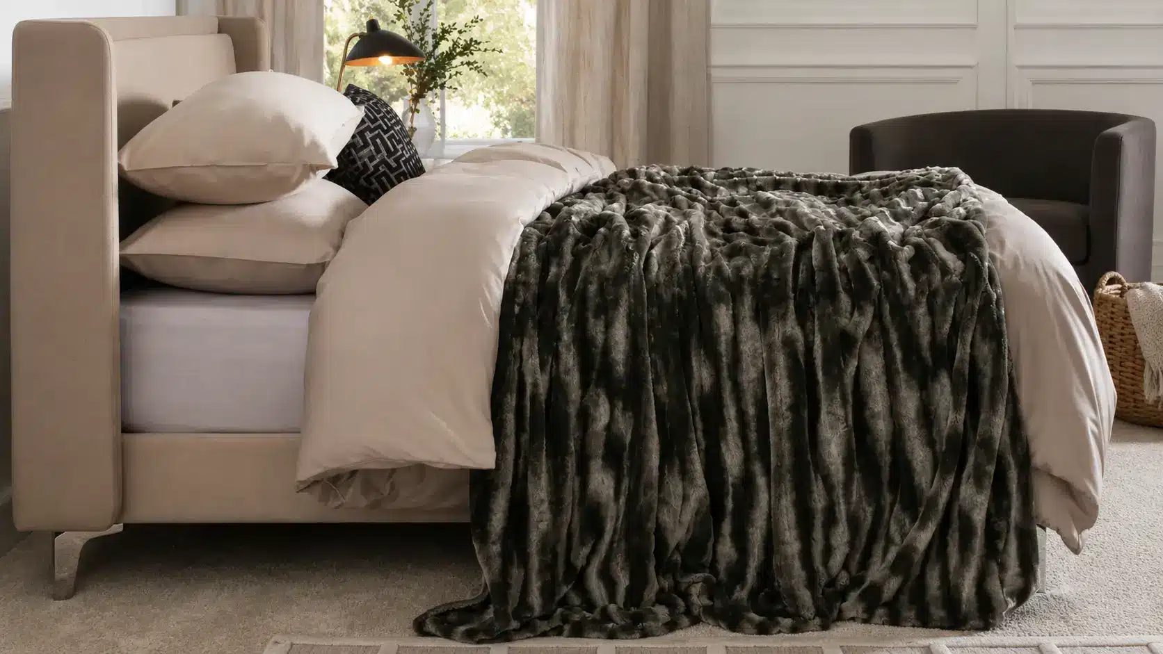 Chunky gray faux fur weighted blanket draped across neatly made bed in a bright, modern bedroom with soft neutral decor.