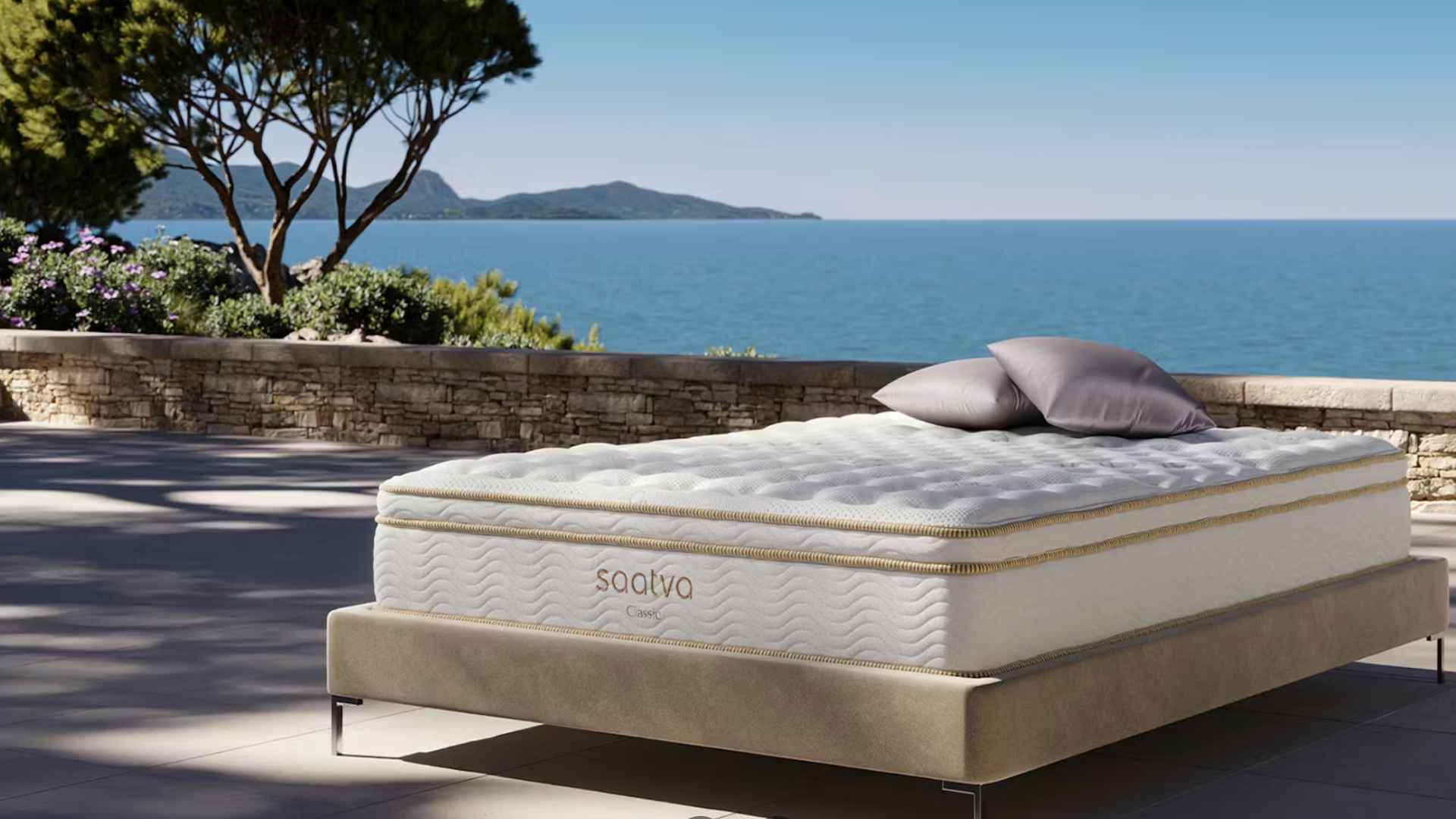 Saatva Classic luxury hybrid mattress with plush pillow top on modern bed frame beside ocean view terrace.
