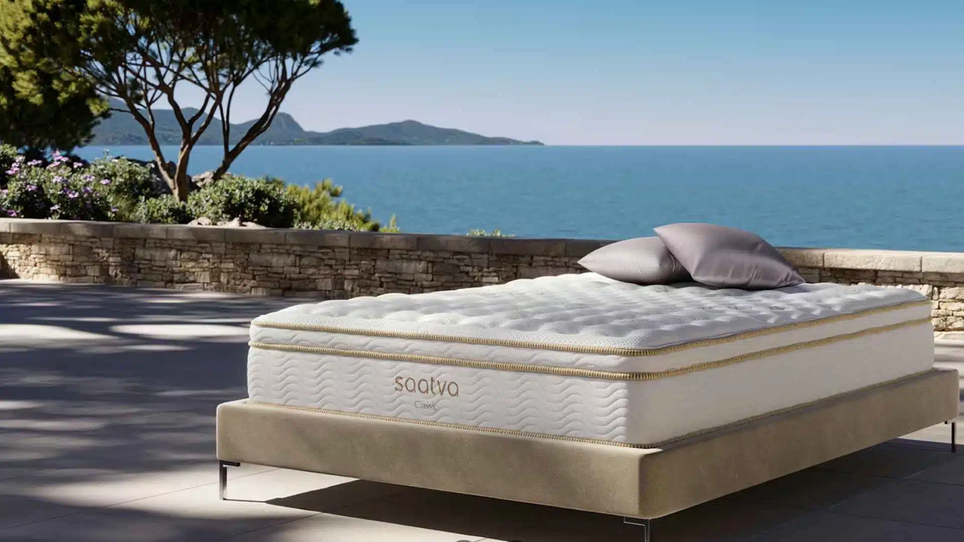 Saatva Classic luxury hybrid mattress with plush pillow top on modern bed frame beside ocean view terrace.