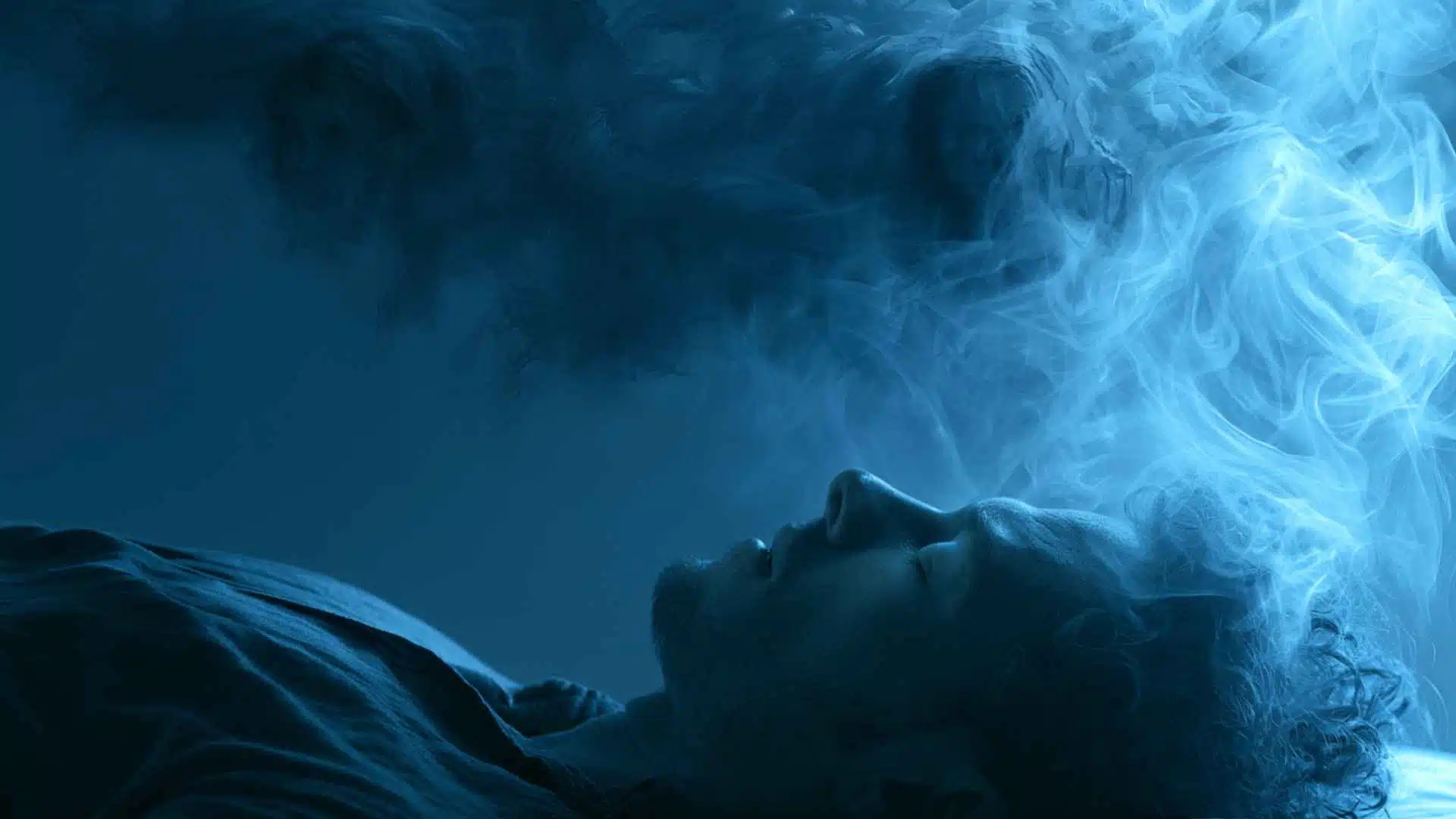Sleeping adult with a distressed expression during REM sleep, soft blue moonlight filtering through bedroom curtains