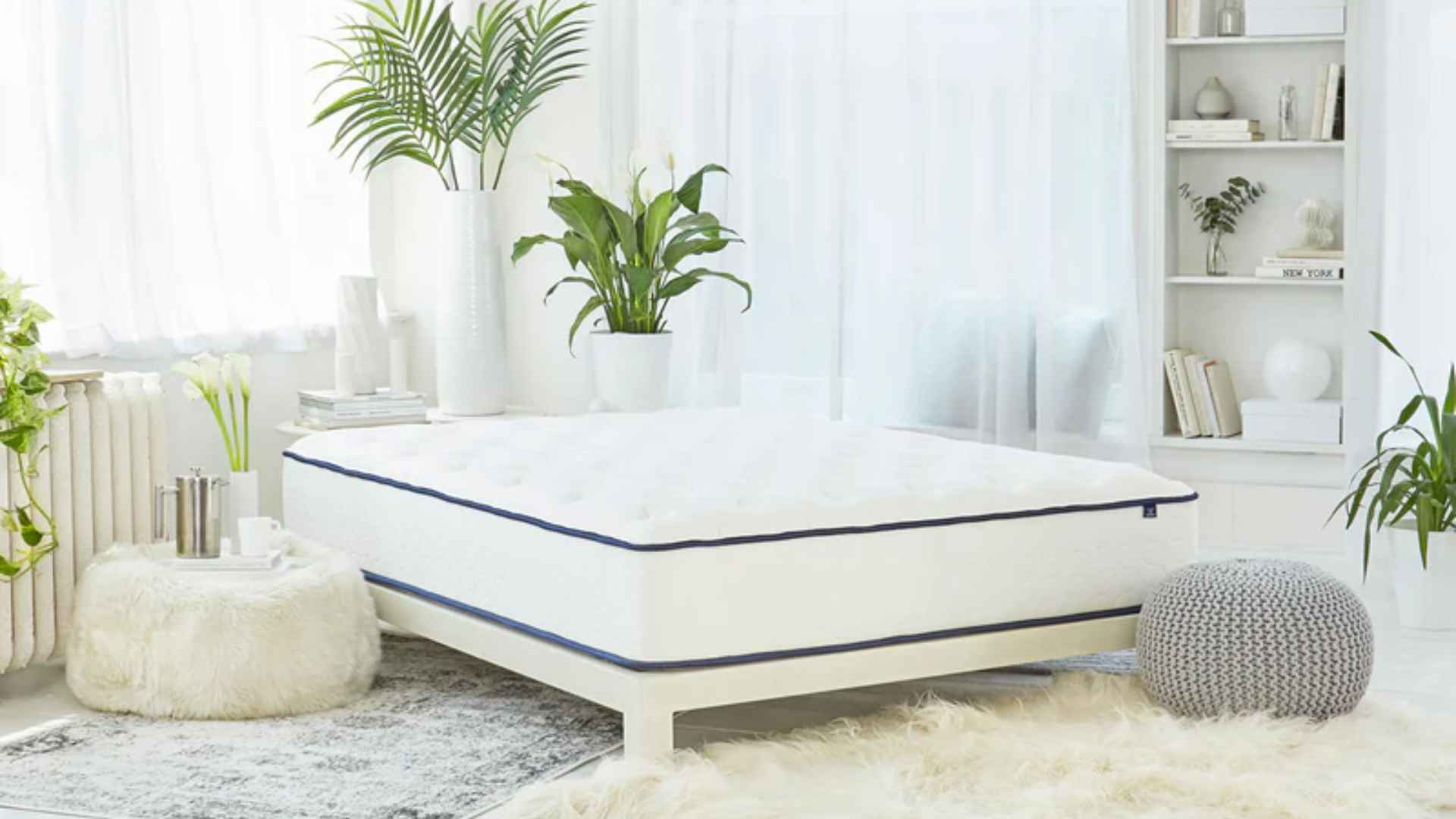Puffy Lux memory foam mattress in bright white bedroom with cozy decor, plants, and soft natural lighting.
