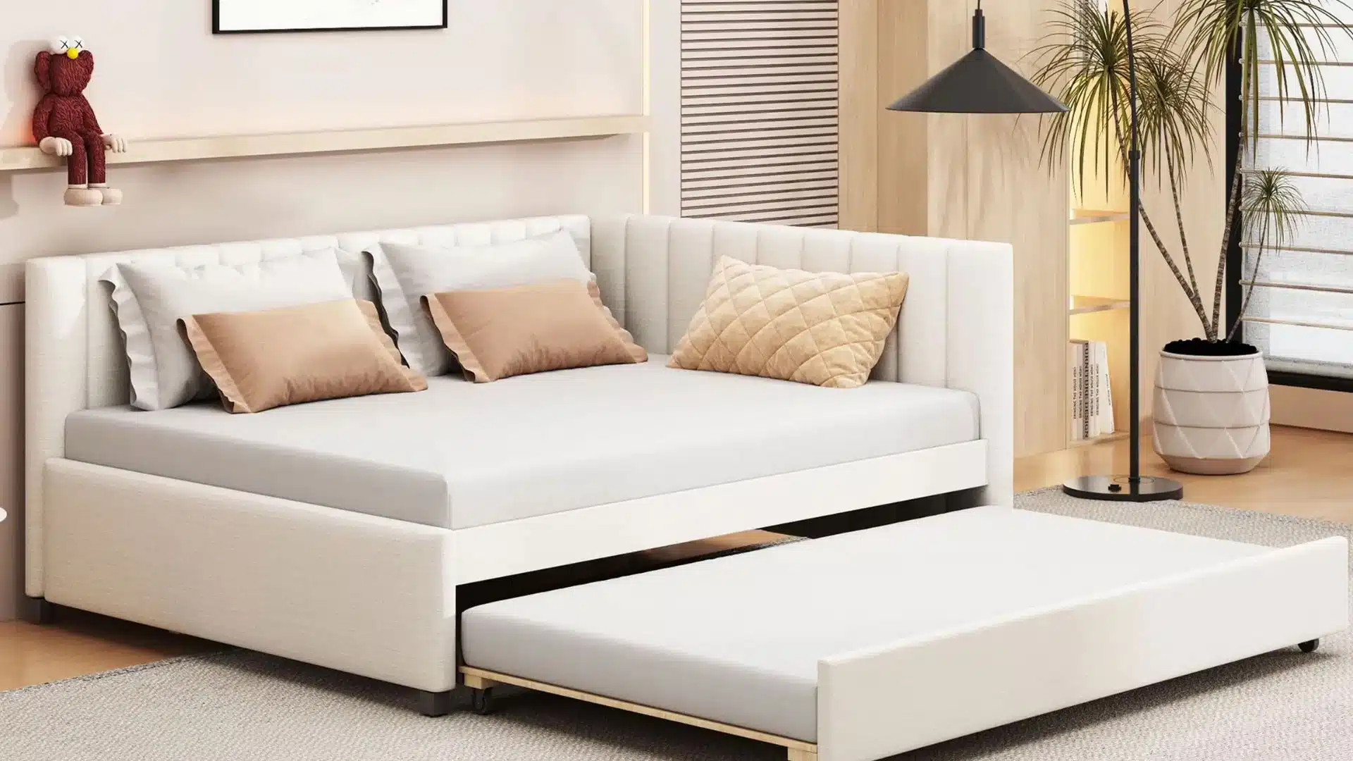 Modern upholstered daybed with a pull-out trundle in a neutral-toned bedroom, with decorative pillows, wood paneling, indoor plants, and a large area rug.