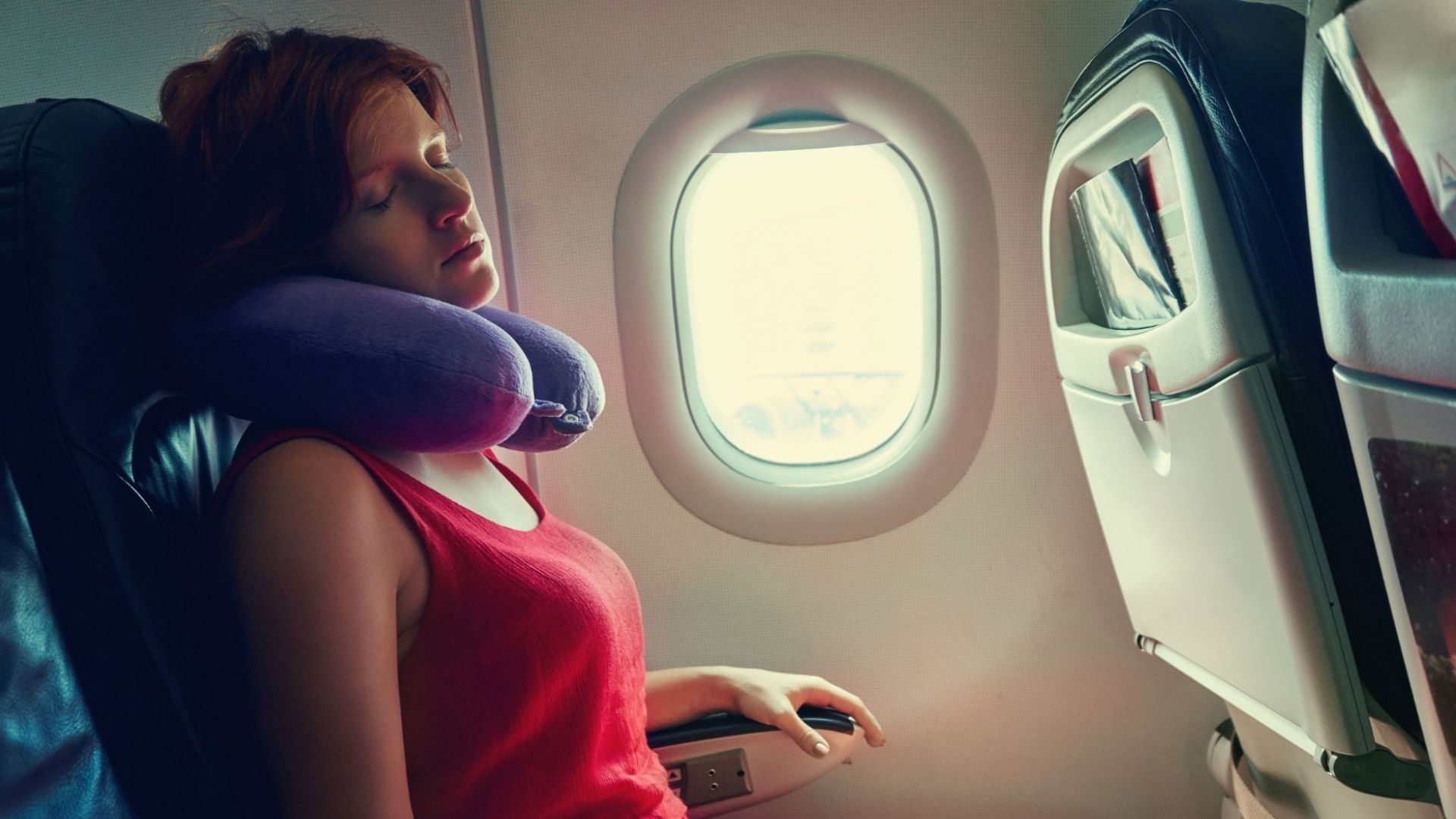 Woman sleeping on an airplane during a long flight while experiencing travel-related sleep disruption